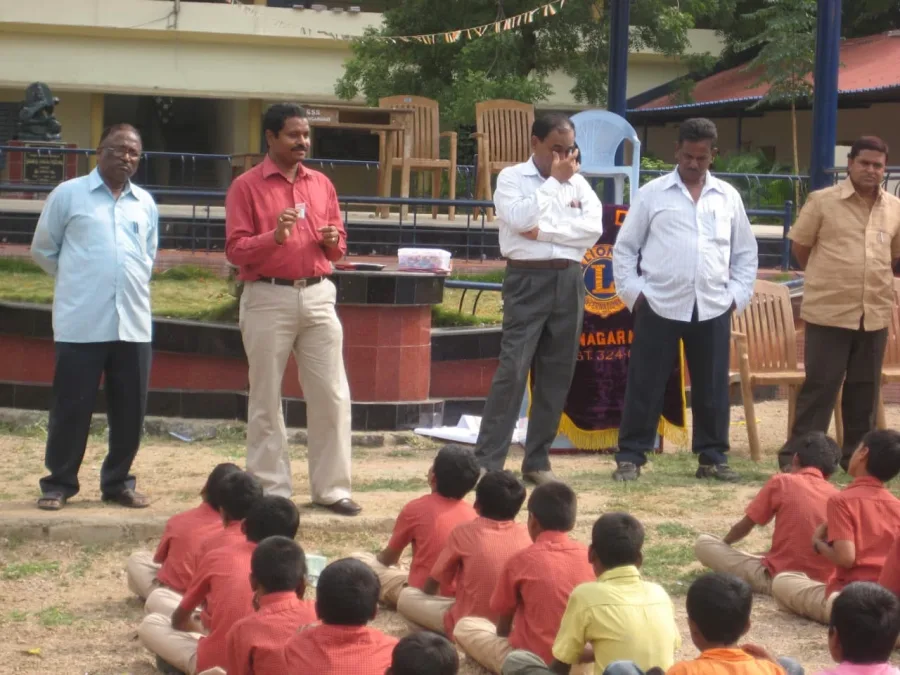 Dr. Srinivas explaining the preventive dose to school students seated in the grounds